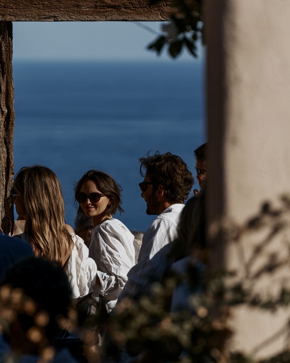 A group at a table above the sea, several conversations at once